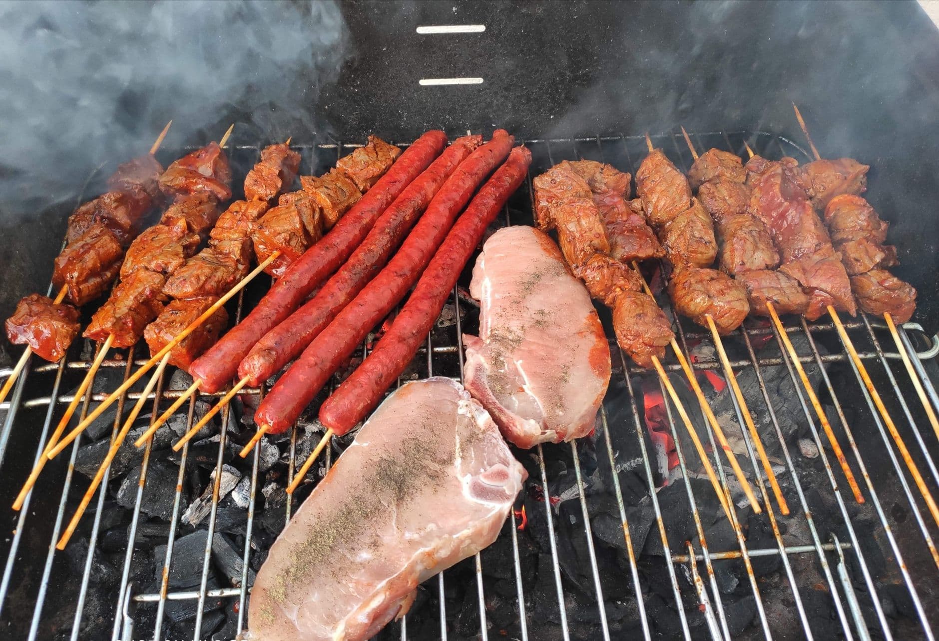 A variety of meats being grilled on a charcoal barbecue. — ventajas y cómo usarlas
